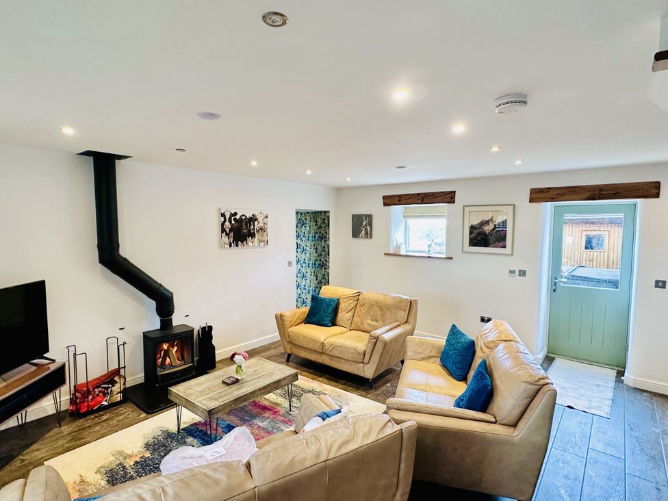 A living room with a wood stove and sofa at Pastures Barn in Bradnop near Leek