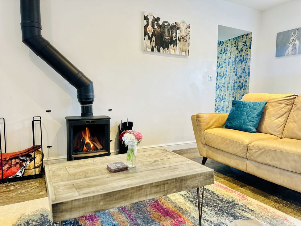 A living room with a fireplace and a coffee table at Pastures Barn in Bradnop near Leek