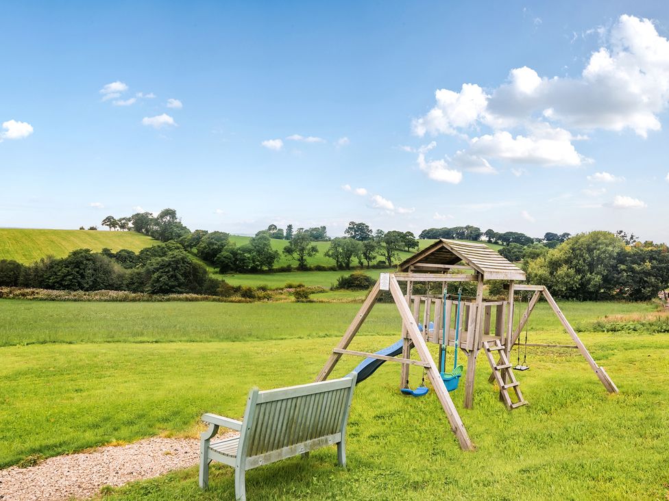 A swing set and bench in a grassy outdoor area at Pastures Barn in Bradnop near Leek