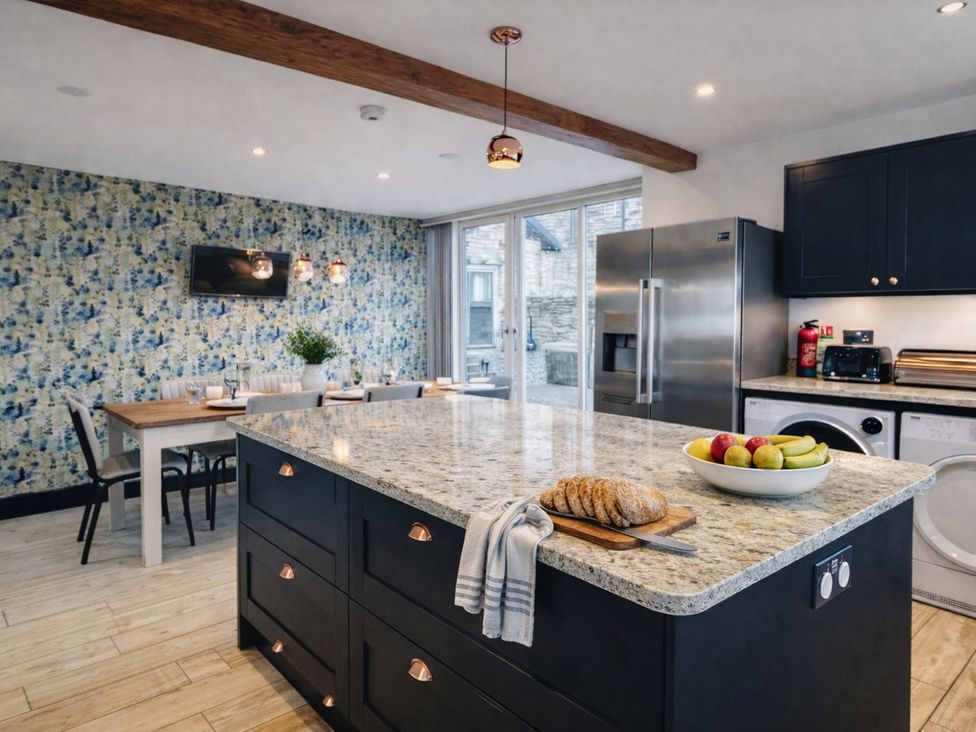 A kitchen with an island, table and appliances at Pastures Barn near Leek