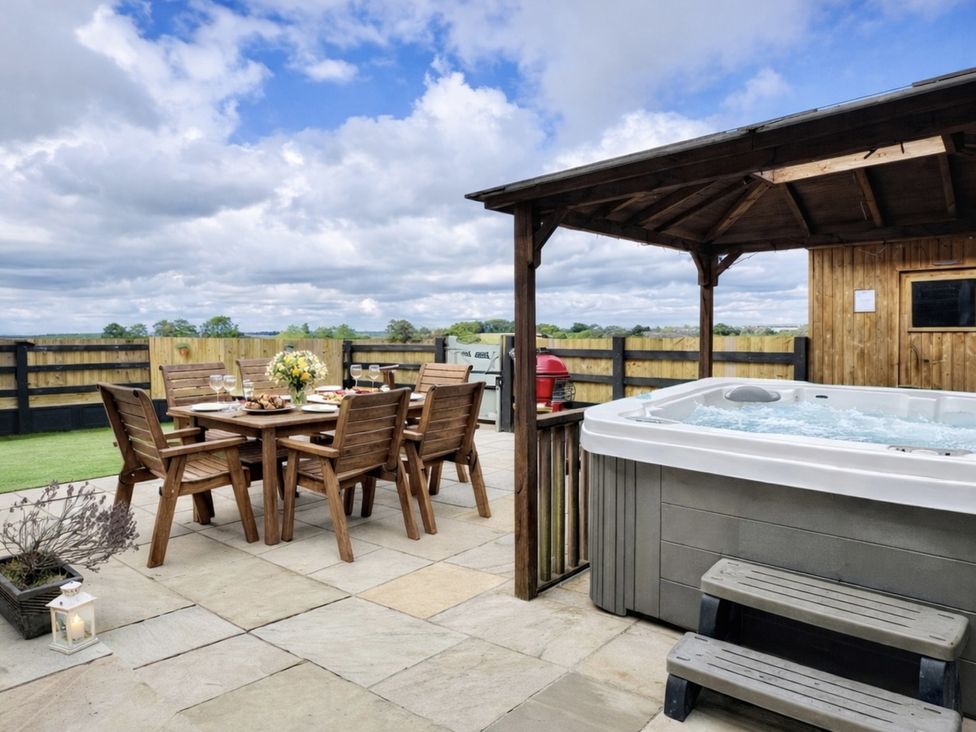 An outdoor dining area with a hot tub at Pastures Barn in Bradnop near Leek
