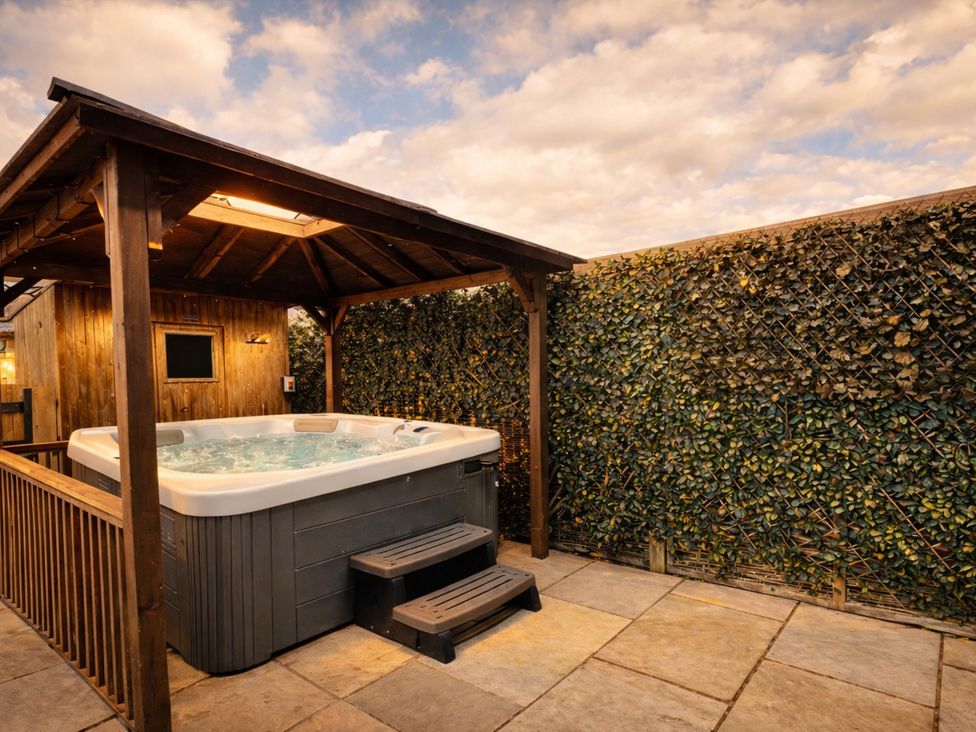 A hot tub under a wooden shelter at Pastures Barn Bradnop near Leek