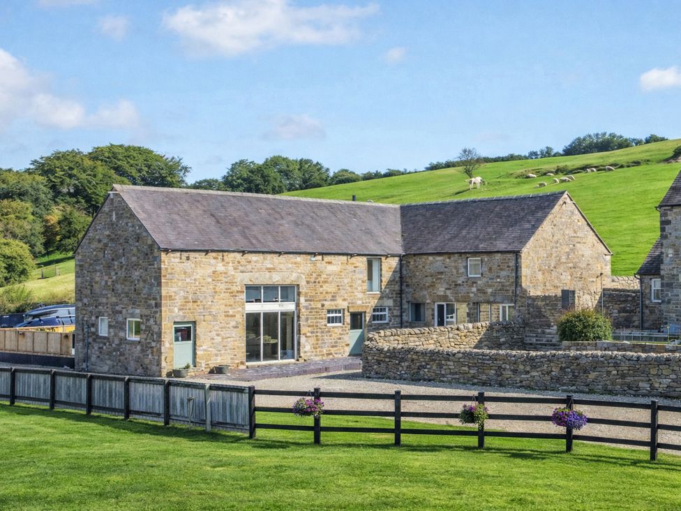 A stone house with a fence and grass at Pastures Barn in Bradnop near Leek