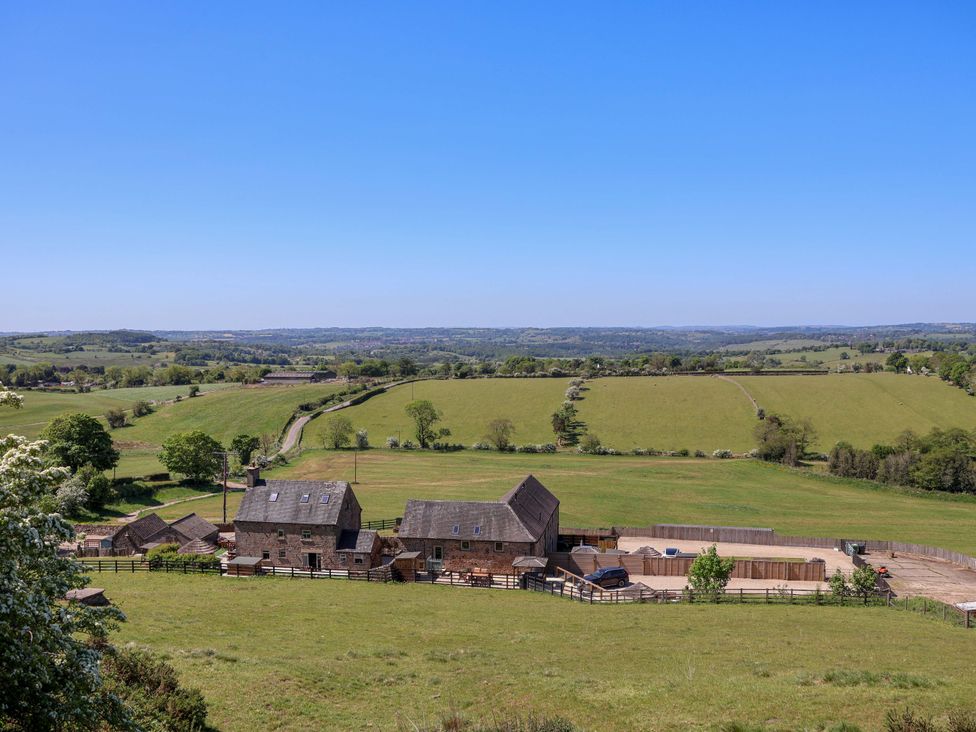 A farmhouse with outbuildings and fenced yards surrounded by green fields and hills at HollyDale Bradnop near Leek
