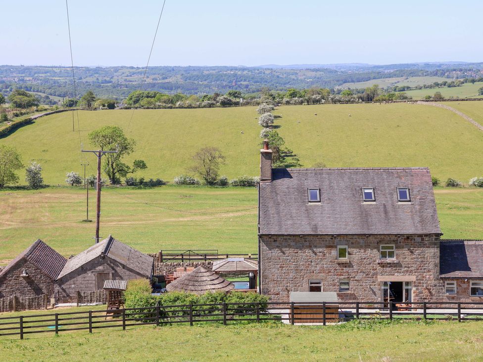 A stone house with outbuildings and a wooden fence in a green field at HollyDale Bradnop near Leek