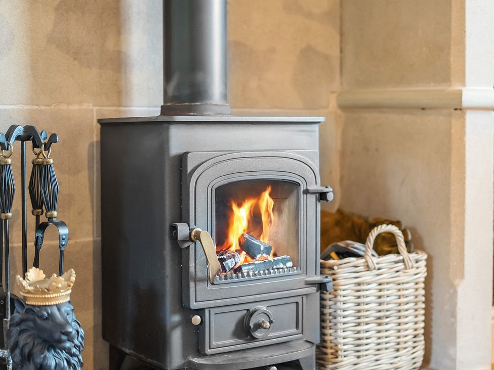A wood stove with fire and tools near a storage basket at HollyDale in Bradnop near Leek