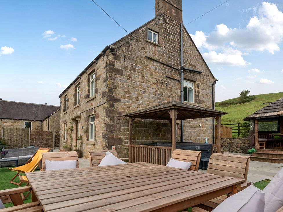 A stone house with a patio table and chairs at HollyDale in Bradnop near Leek