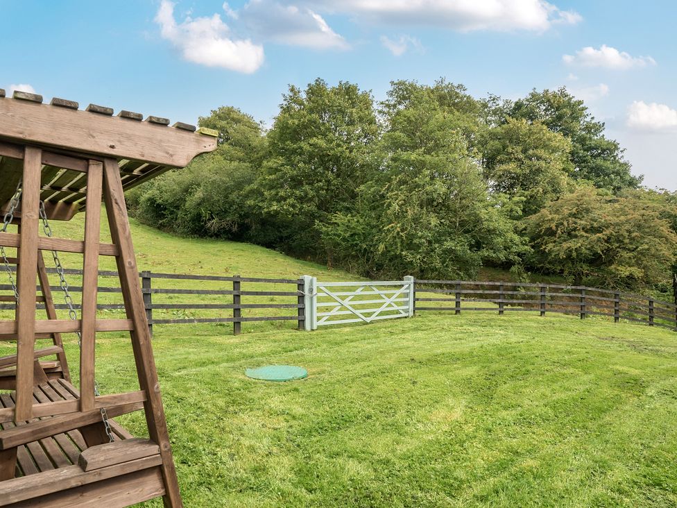 An outdoor area with a swing set and fence at HollyDale in Bradnop near Leek