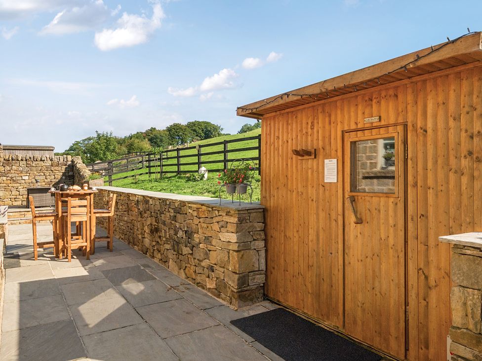 An outdoor area with a wooden shed and a stone wall at HollyDale in Bradnop near Leek