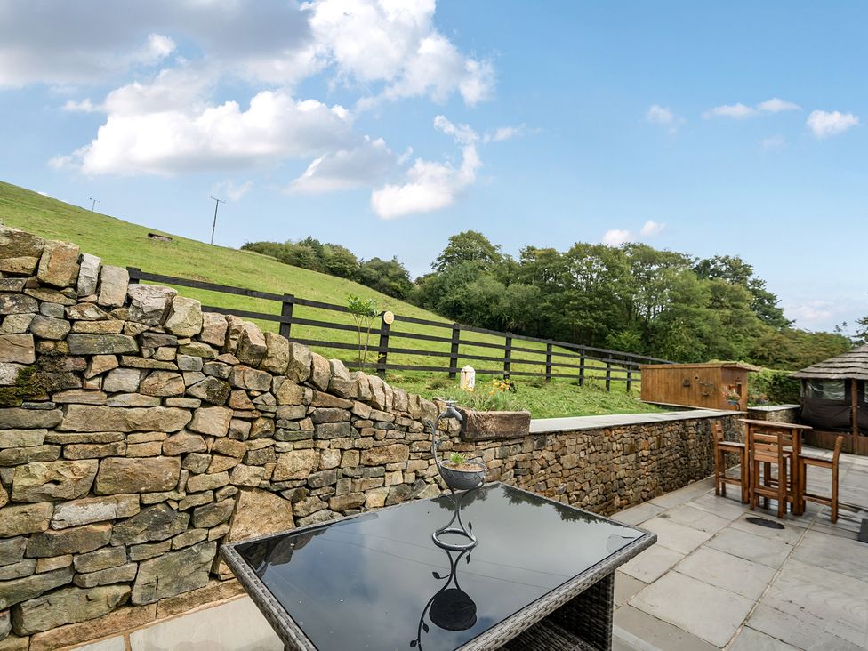 An outdoor area with a stone wall and a bar table at HollyDale in Bradnop near Leek