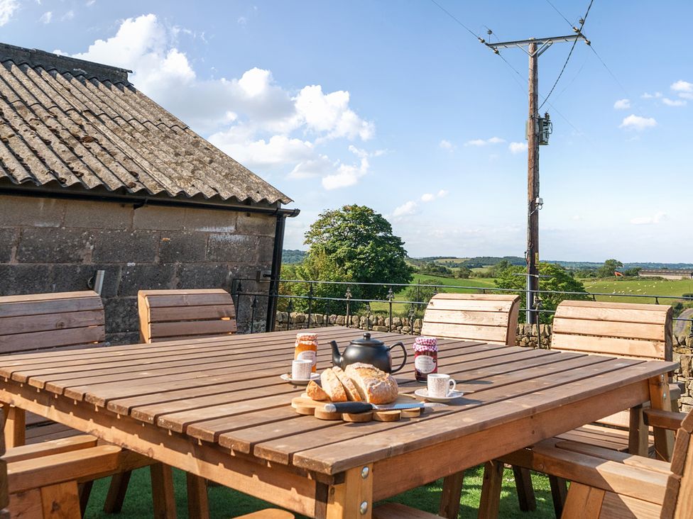 An outdoor dining area with a wooden table and chairs at HollyDale in Bradnop near Leek