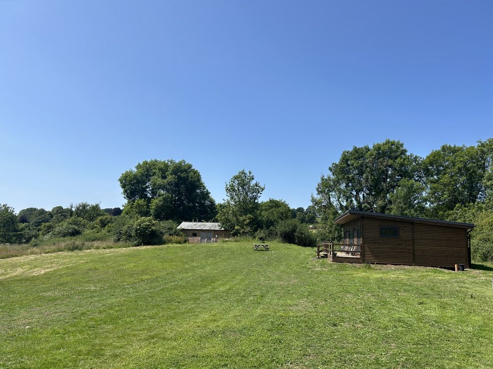 A wooden cabin and picnic table on grass at Foxglove in Higher Wambrook near Chard