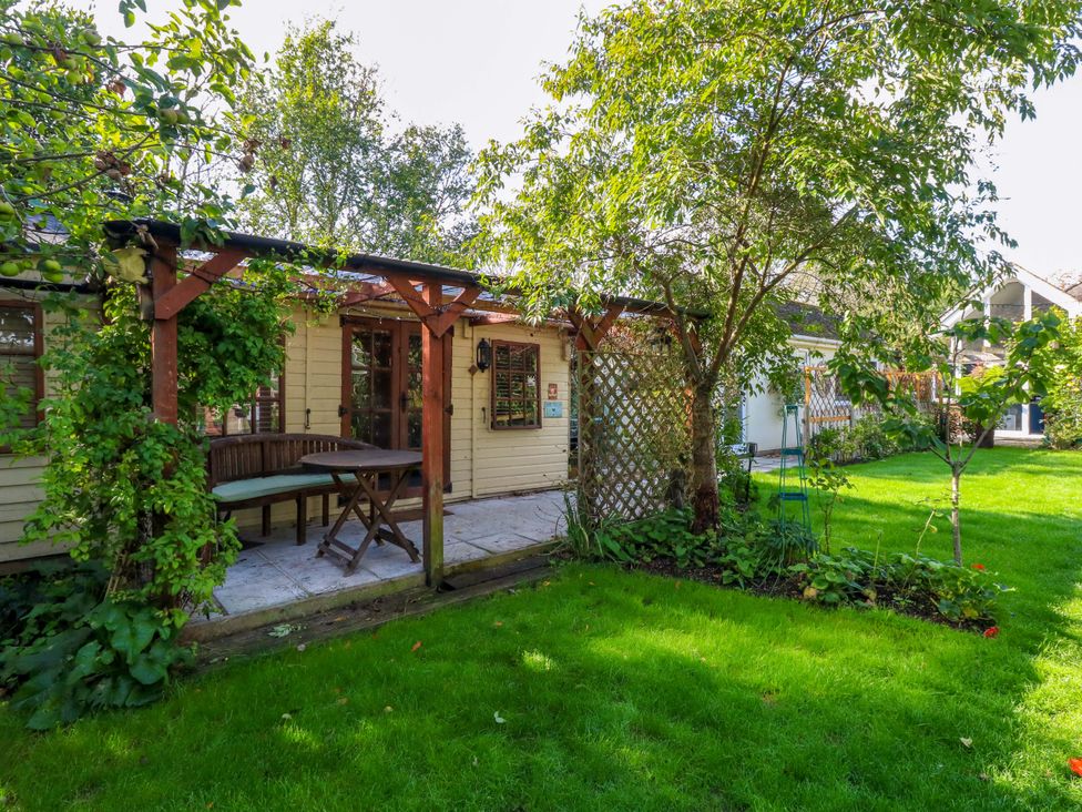 A garden with a house, table, and trees at The Cabin at Little Timbers Ringwood