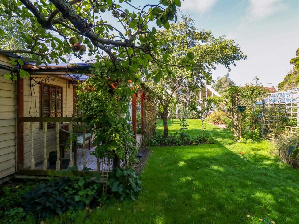 A garden with a house and trees at The Cabin at Little Timbers Ringwood