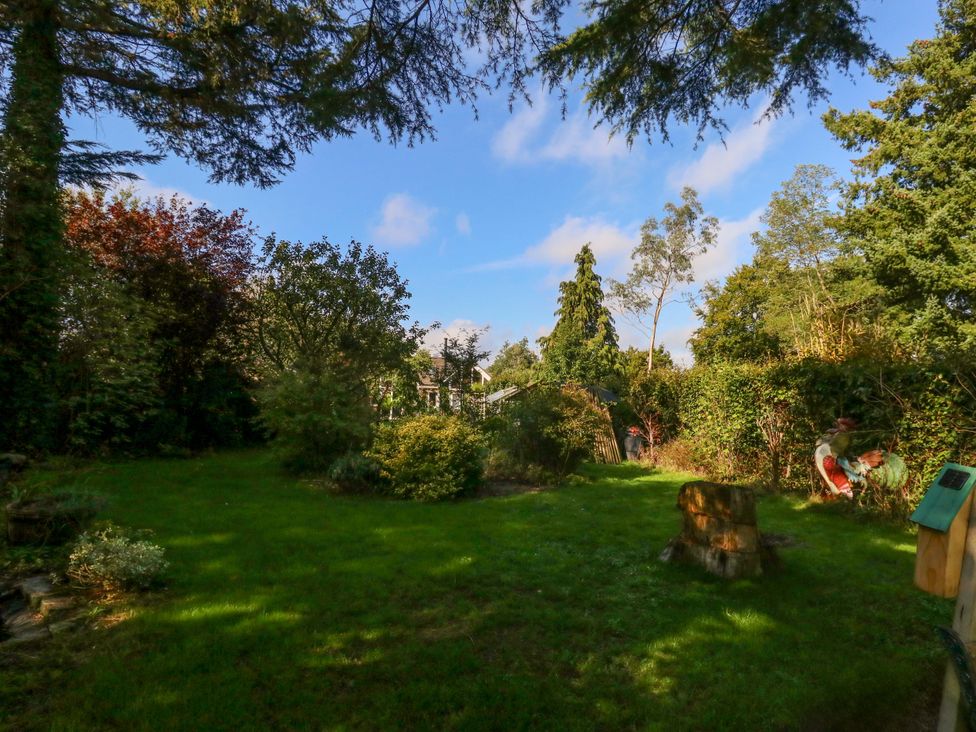 A garden with trees and a birdhouse at The Cabin at Little Timbers Ringwood