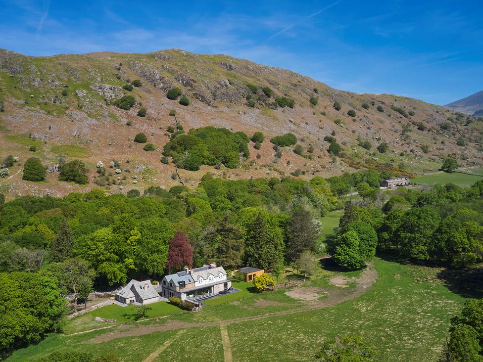 A countryside farmhouse with surrounding trees and hills at Eskdale Retreat in Boot