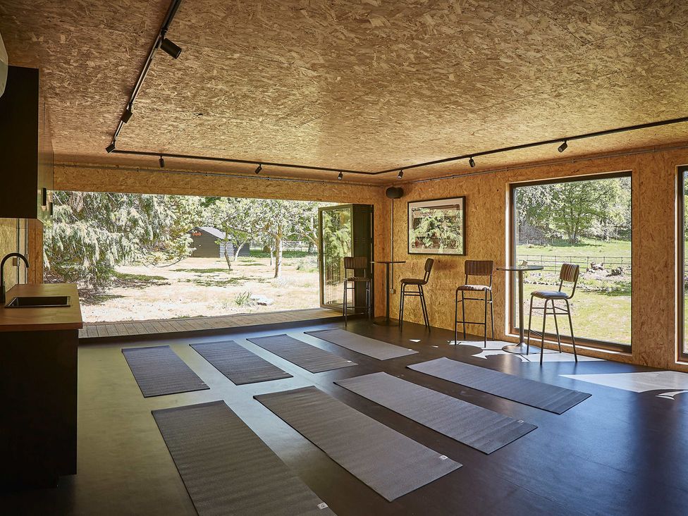 A room with exercise mats on the floor and bar stools by tables next to large windows at Eskdale Retreat in Boot