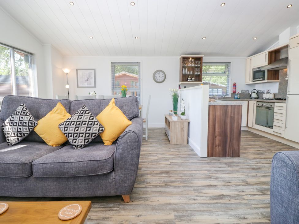 A living room with a sofa and dining area at Dovedale Lodge in Troutbeck Bridge