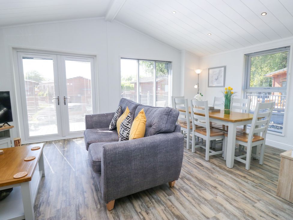 A living room with a sofa and dining table at Dovedale Lodge Troutbeck Bridge