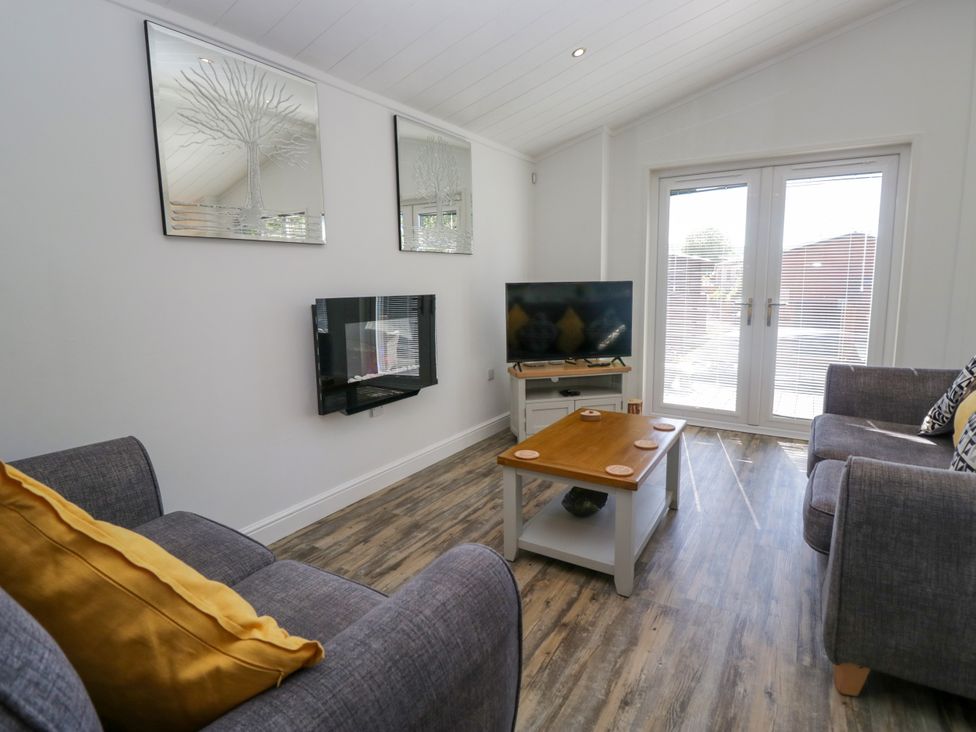A living room with a sofa and television at Dovedale Lodge in Troutbeck Bridge