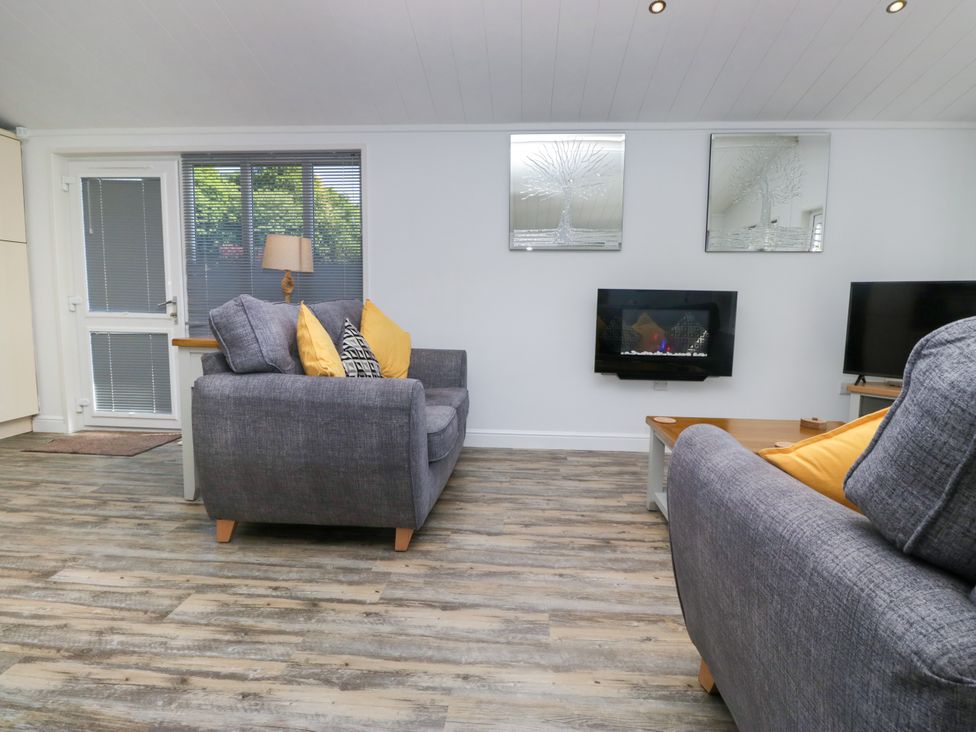 A living room with a sofa and television at Dovedale Lodge in Troutbeck Bridge