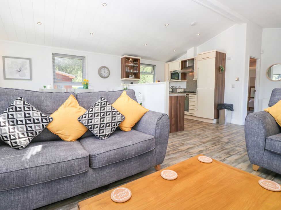 A living room with a sofa and kitchen area at Dovedale Lodge Troutbeck Bridge