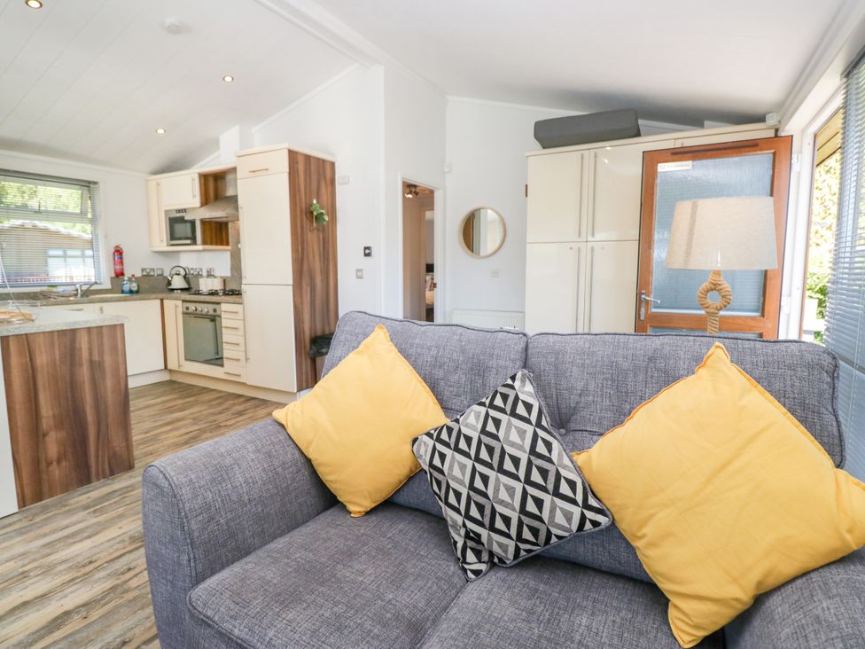 A living room with a sofa and kitchen area at Dovedale Lodge Troutbeck Bridge