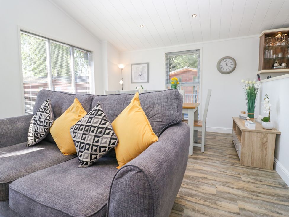 A living room with a sofa and dining area at Dovedale Lodge in Troutbeck Bridge