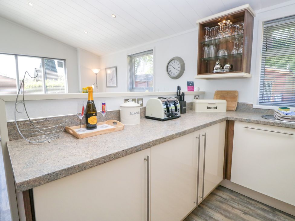 A kitchen with a toaster, storage containers, and a clock at Dovedale Lodge, Troutbeck Bridge