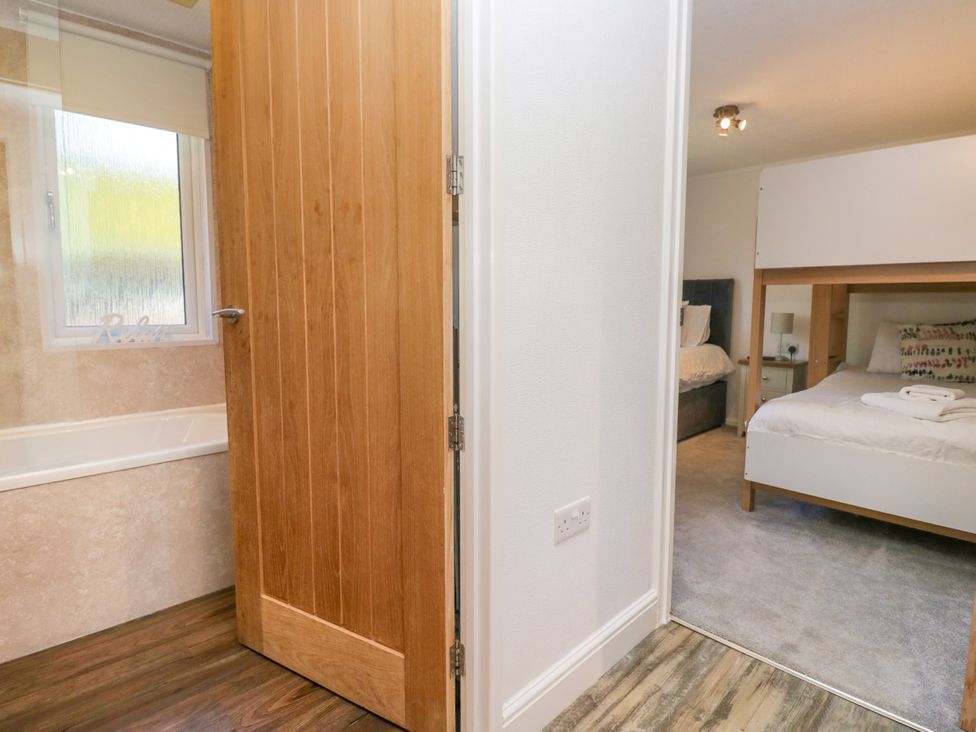 A bedroom with a bed and door at Dovedale Lodge Troutbeck Bridge