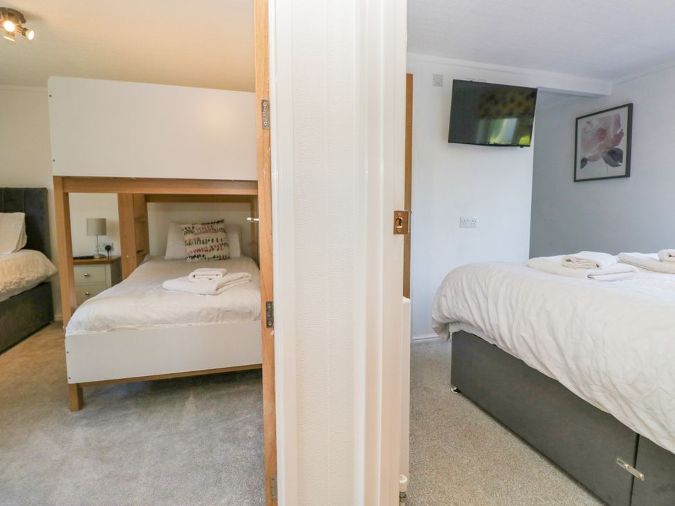 A bedroom with a bunk bed and a double bed at Dovedale Lodge in Troutbeck Bridge