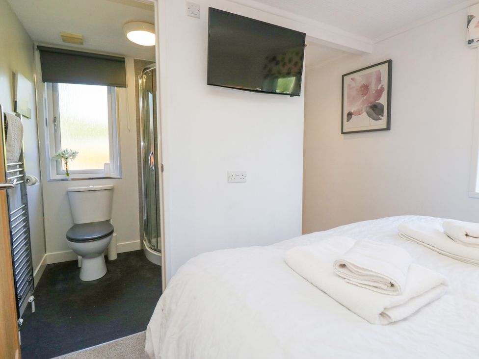A bedroom with a bed and bathroom area at Dovedale Lodge Troutbeck Bridge