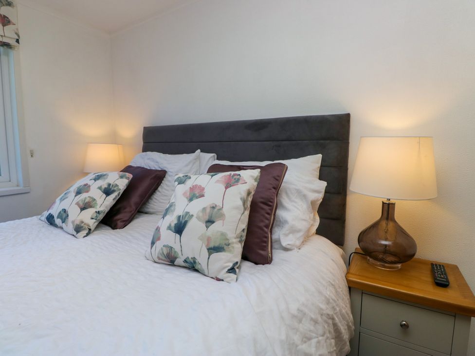 A bedroom with a bed and bedside table at Dovedale Lodge, Troutbeck Bridge