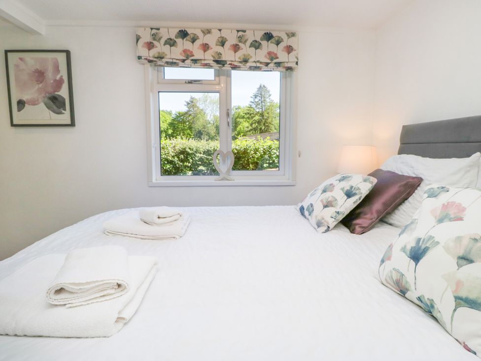 A bedroom with a bed and window at Dovedale Lodge Troutbeck Bridge