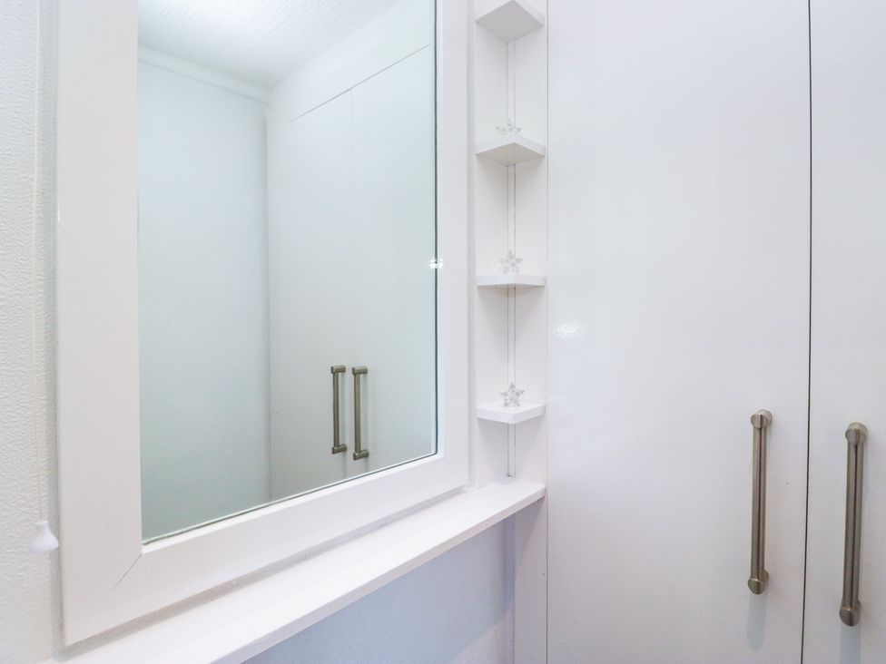 A mirror and cabinet in a bathroom at Dovedale Lodge Troutbeck Bridge