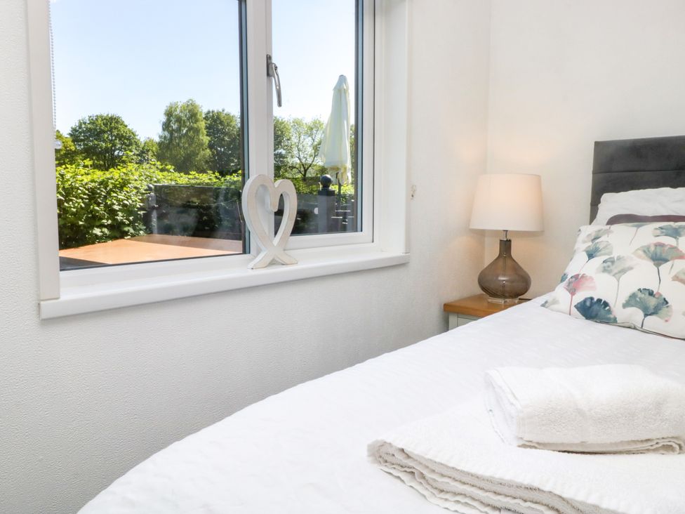 A bedroom with a bed, lamp, and window at Dovedale Lodge Troutbeck Bridge