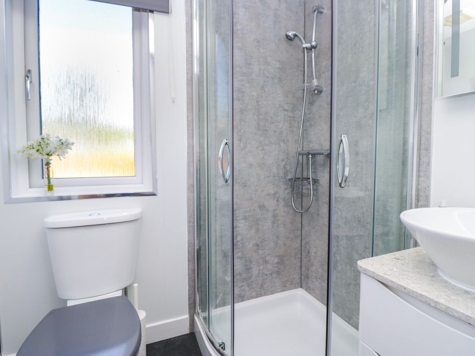 A bathroom with a shower, toilet, and sink at Dovedale Lodge, Troutbeck Bridge