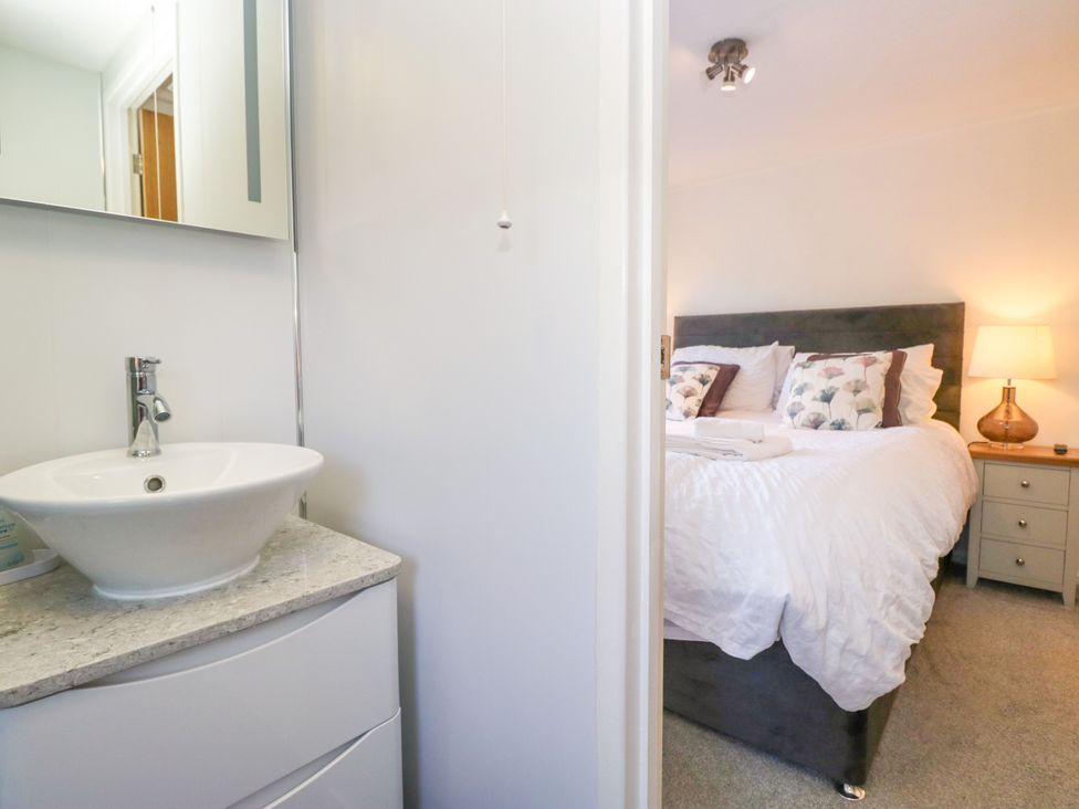 A bedroom with a bed and sink at Dovedale Lodge in Troutbeck Bridge