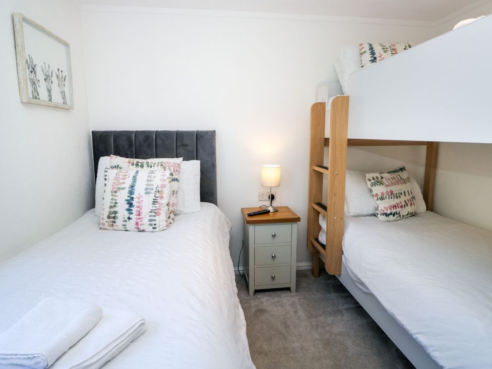 A bedroom with a single bed and a bunk bed at Dovedale Lodge Troutbeck Bridge