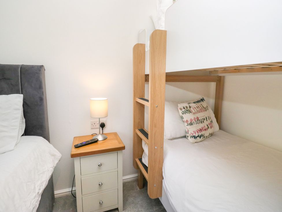 A bedroom with a bunk bed and a single bed at Dovedale Lodge in Troutbeck Bridge