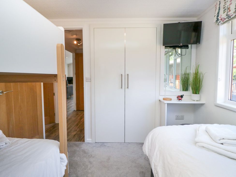 A bedroom featuring a bunk bed and a television at Dovedale Lodge in Troutbeck Bridge