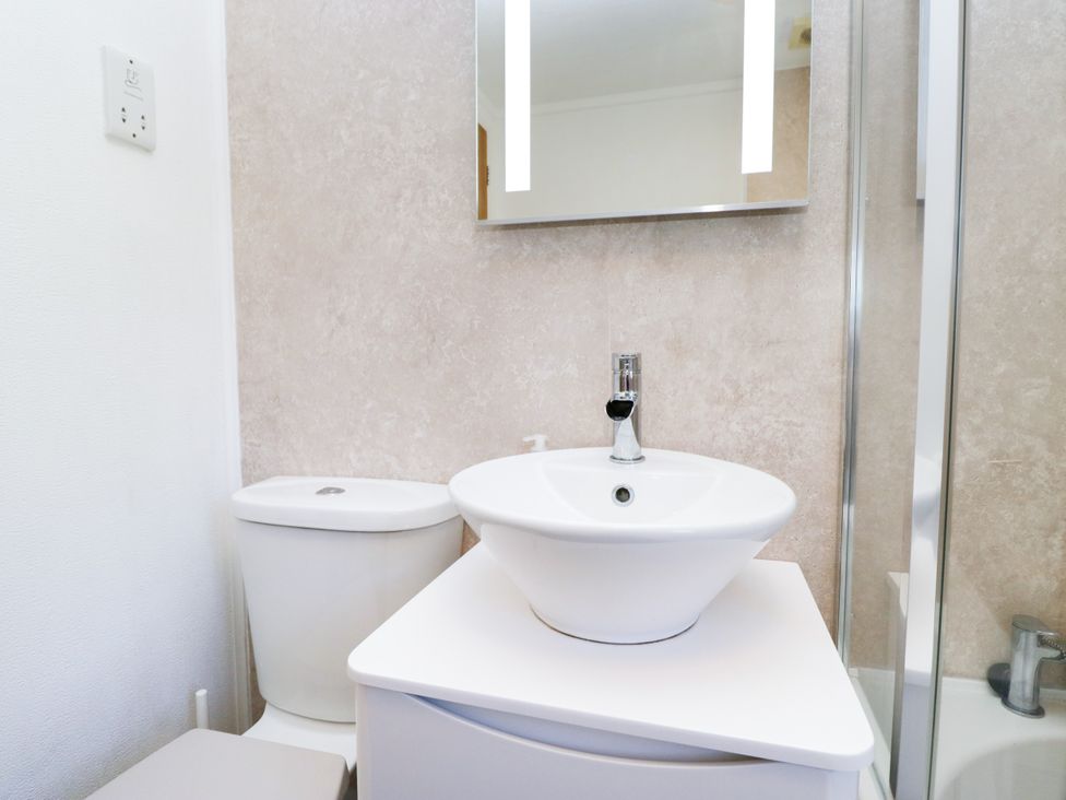 A bathroom with a sink, toilet, and shower at Dovedale Lodge, Troutbeck Bridge