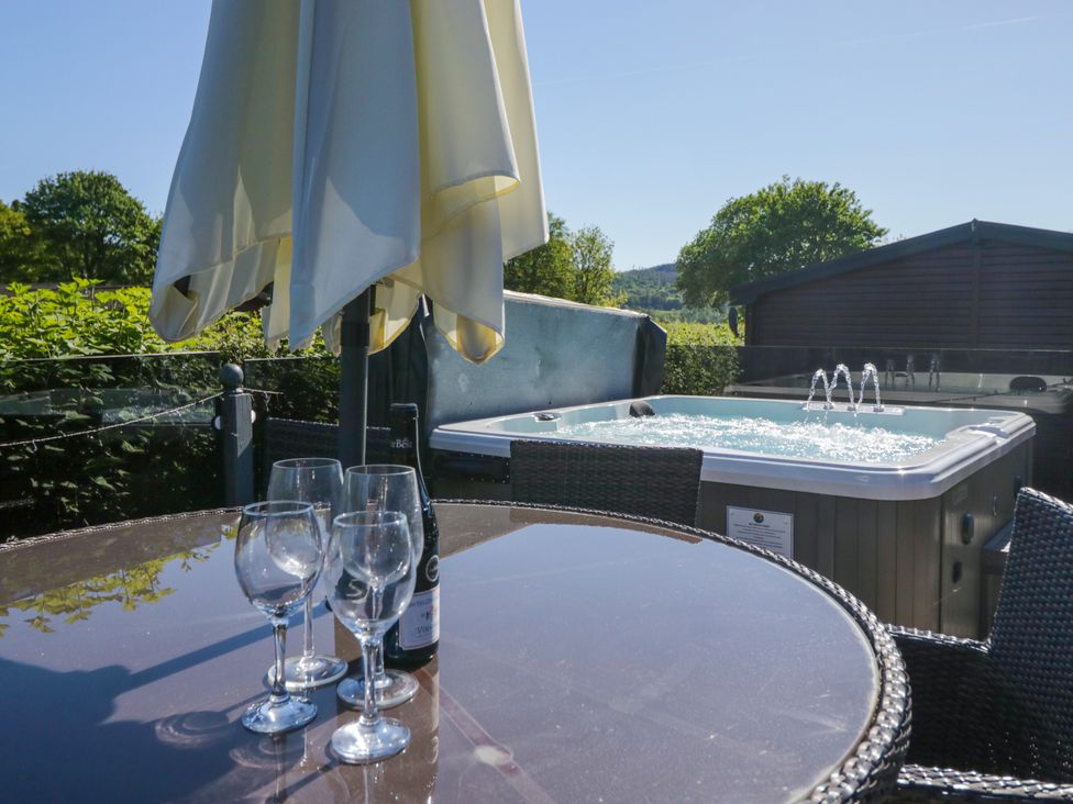 An outdoor area with a hot tub and a table set at Dovedale Lodge in Troutbeck Bridge