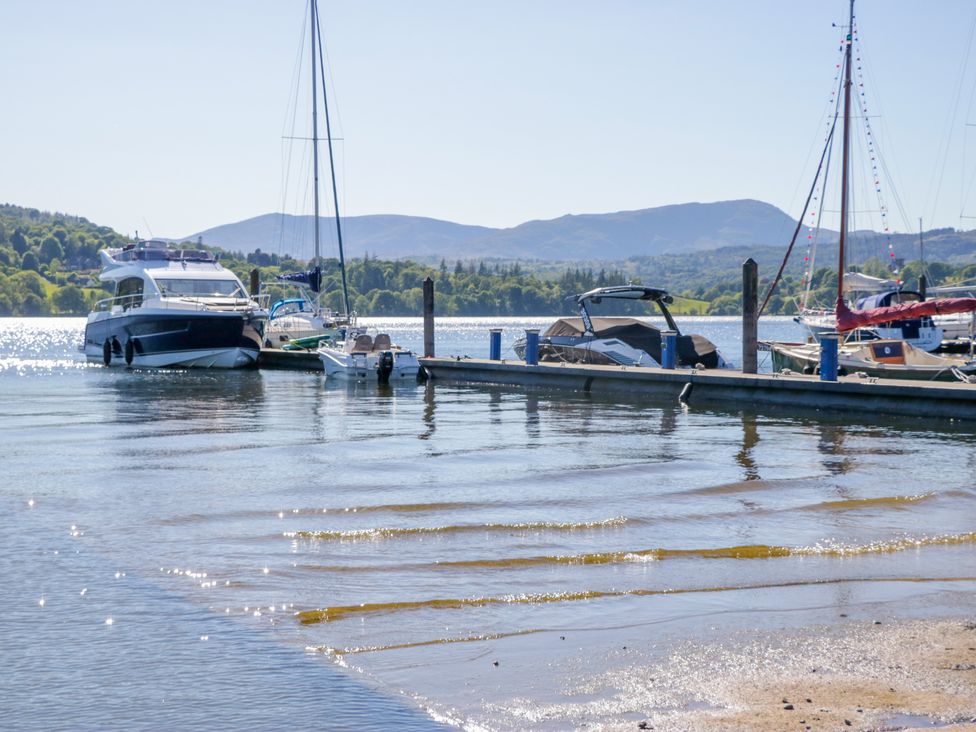Boats at a dock on water with mountains in the background at Dovedale Lodge in Troutbeck Bridge