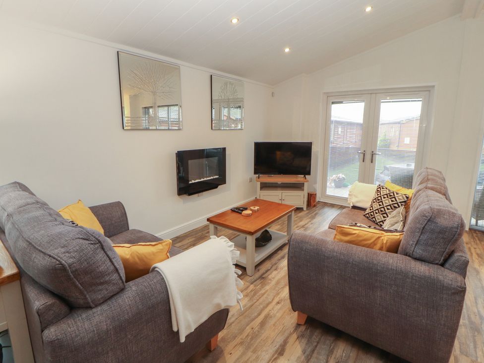 A living room with a coffee table and television at Dovedale Lodge in Bowness 70, White Cross Bay near Windermere