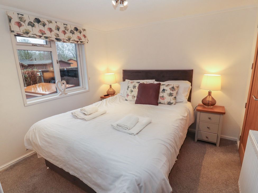 A bedroom with a bed and bedside tables at Dovedale Lodge Bowness 70 White Cross Bay near Windermere