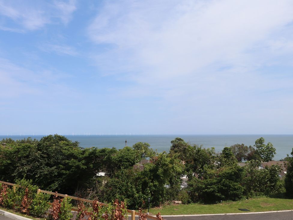 A view of the sea with wind turbines and trees at Golygfa Gele in Llanddulas