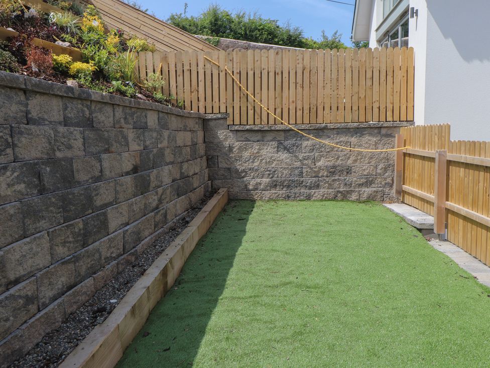 A garden with artificial grass and a stone wall at Golygfa Gele Llanddulas