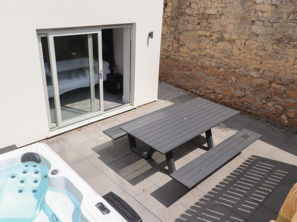 An outdoor area with a hot tub and a table at Golygfa Gele in Llanddulas