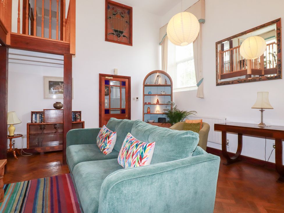 A living room with a teal sofa and bookshelf at Rosemaddon in Crantock